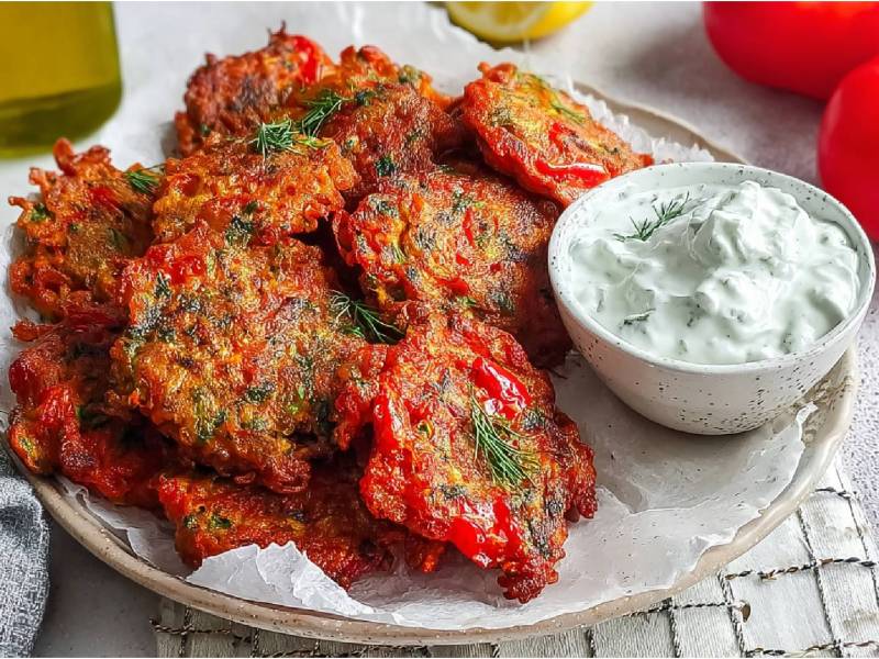 Teller mit mehreren Tomatokeftedes, eine Schale mit hellem Dip daneben