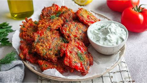 Teller mit mehreren Tomatokeftedes, eine Schale mit hellem Dip daneben