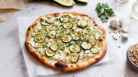 eine Zucchini-Ricotta-Pizza mit Pinienkernen auf einem Tisch