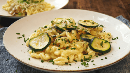 Ein Teller Zucchini-Spätzle-Pfanne, bestreut mit Schnittlauch.