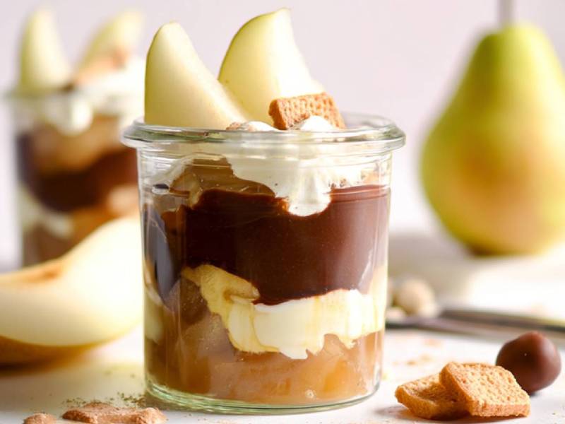 Zwei Gläser Birne Helene Trifle auf einem Tisch, frische Birnen im Hintergrund