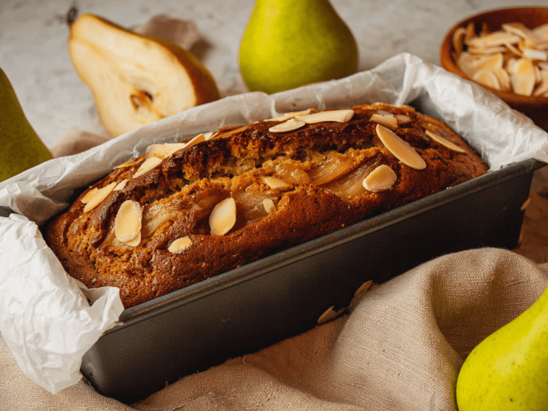 Birnen-Mandel-Kuchen aus der Kastenform, daneben frische Birnen.