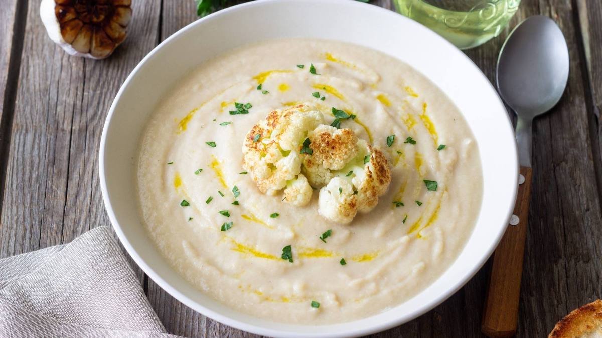 Eine Schüssel mit Blumenkohl-Bohnen-Suppe, garniert mit geröstetem Blumenkohl.