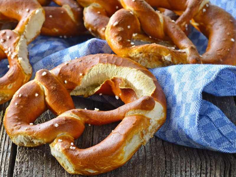 Brezeln selbst backen: frisch gebackene Brezeln auf einem blau karierten Tuch.