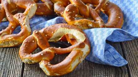 Brezeln selbst backen: frisch gebackene Brezeln auf einem blau karierten Tuch.