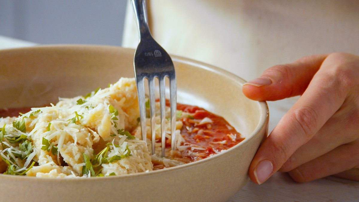 Nahaufnahme: Ein Teller mit Brotpasta mit Tomatensoße und geriebenem Hartkäse serviert.