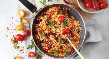 Eine Couscous-Pfanne mit Kidneybohnen, Paprika und frischen Tomaten in der Draufsicht.