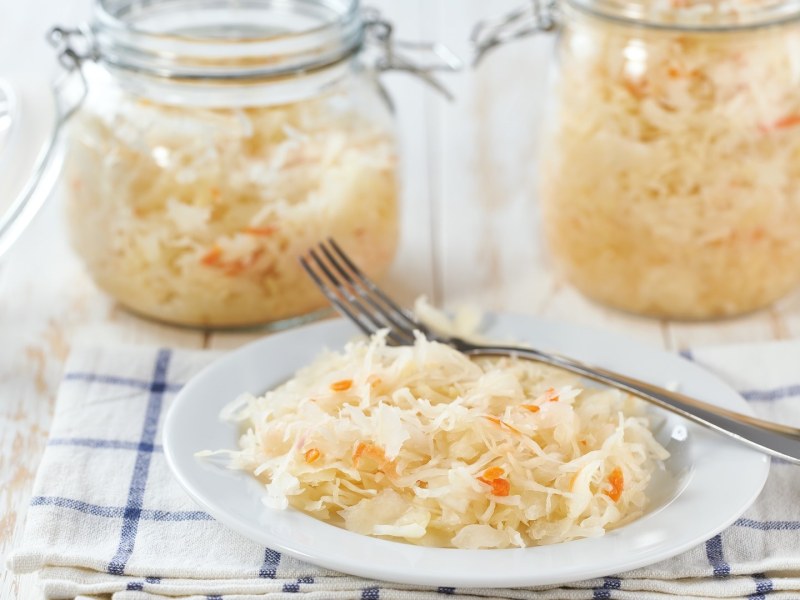Zwei Gläser und eine Schale fermentierter Krautsalat mit Möhren.