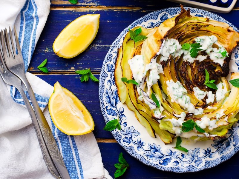 Gebratener Spitzkohl mit Walnusscreme auf einem blau-weiß gemusterten Teller.