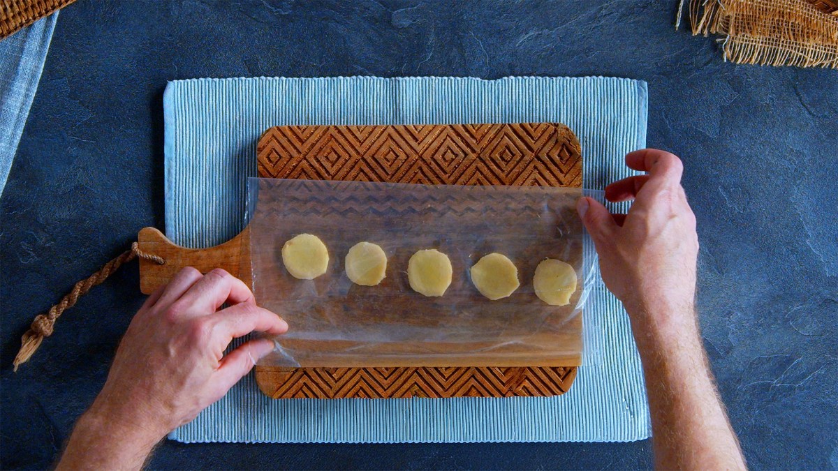 Ein Holzbrett, auf dem ein Gefrierbeutel mit Ingwerscheiben platziert ist.