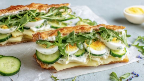 Zwei Kartoffelsandwiches mit Ei, Gurke, Käse und Rucola.