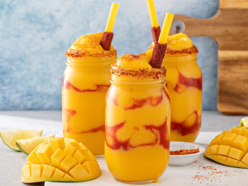 Drei Gläser mit Mangonada, einem mexikanischen Drink aus Mango und Chilisoße.