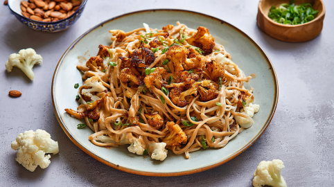 Ein Teller Nudeln mit Blumenkohl und Erdnussbutter.