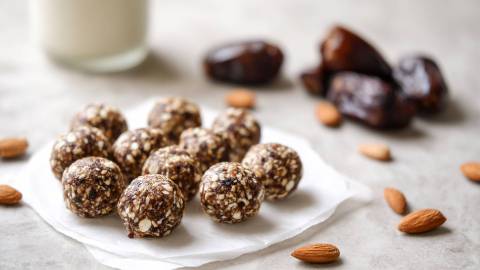 Pflaumen-Mandel-Energy-Balls auf einem Tisch, getrocknete Pflaumen im Hintergrund