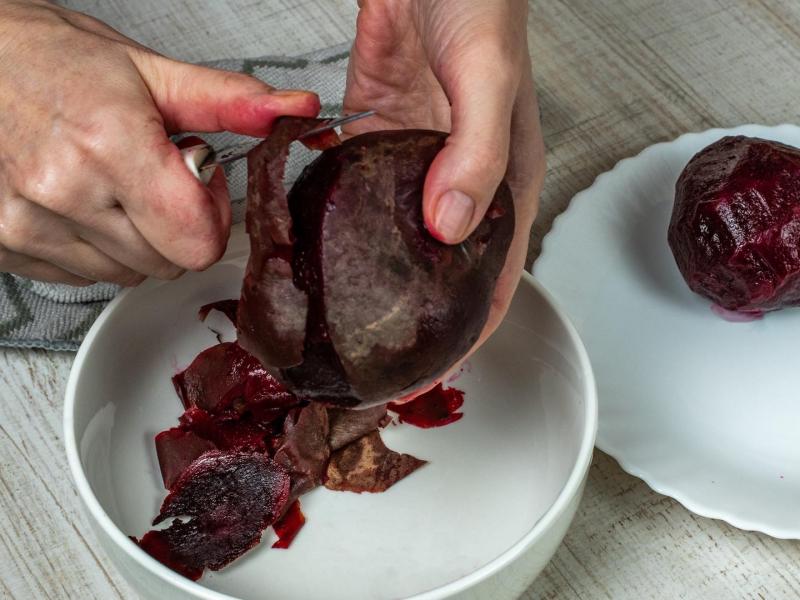 Rote Bete schälen: Eine Person schält eine Rote Bete mit einem Messer.