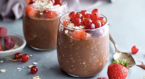Zwei Gläser Schokopudding-Oats mit frischen Beeren.