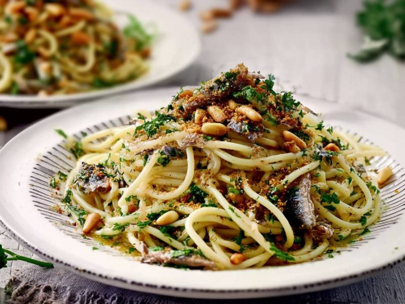 Zwei Teller mit Spaghetti mit Ölsardinen auf einem Tisch