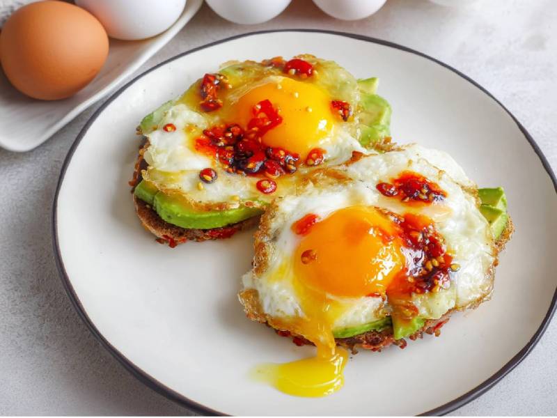Teller mit zwei Avocado-Toast mit Ei und Crispy Chili Oil