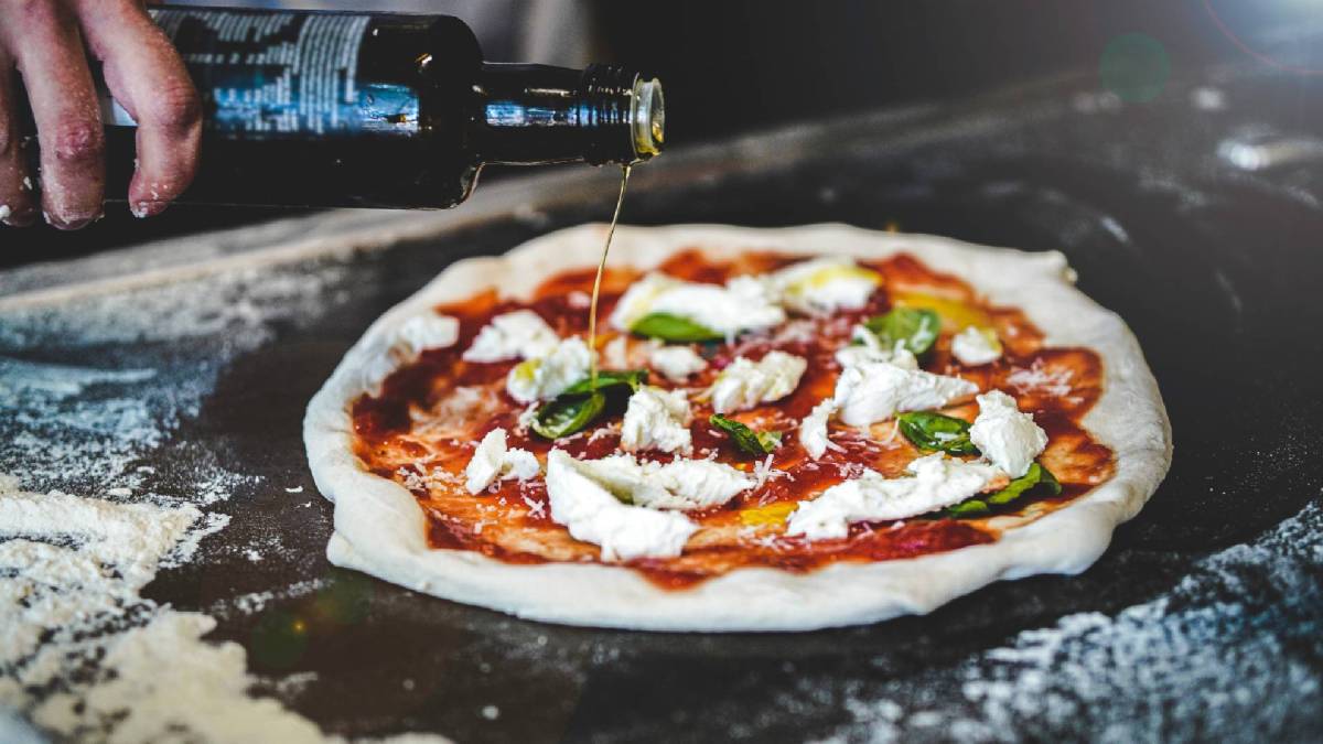 10 Fakten über Pizza: Pizzabäcker beim Zubereiten einer Pizza