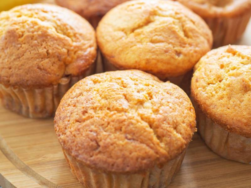 Holzbrett mit Bananen-Quark-Muffins, Banane im Hintergrund