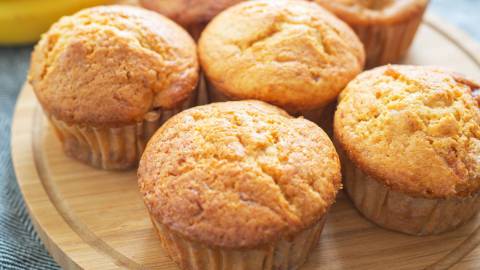 Holzbrett mit Bananen-Quark-Muffins, Banane im Hintergrund