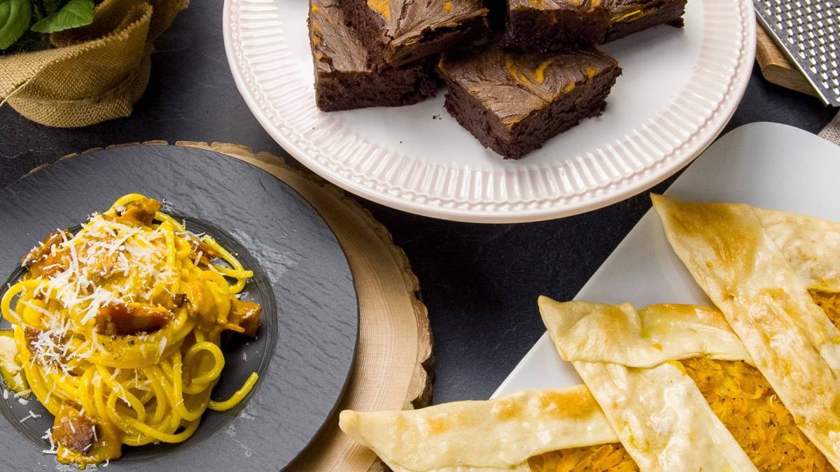 Draufsicht: ein Teller mit Kürbis-Brownies, ein Teller mit Kürbis-Carbonara, ein Teller mit Kürbis-Bolani. Eine Zutat, drei Rezepte.