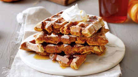Mehrere French-Toast-Kürbis-Waffeln auf einem Teller übereinander gestapelt.