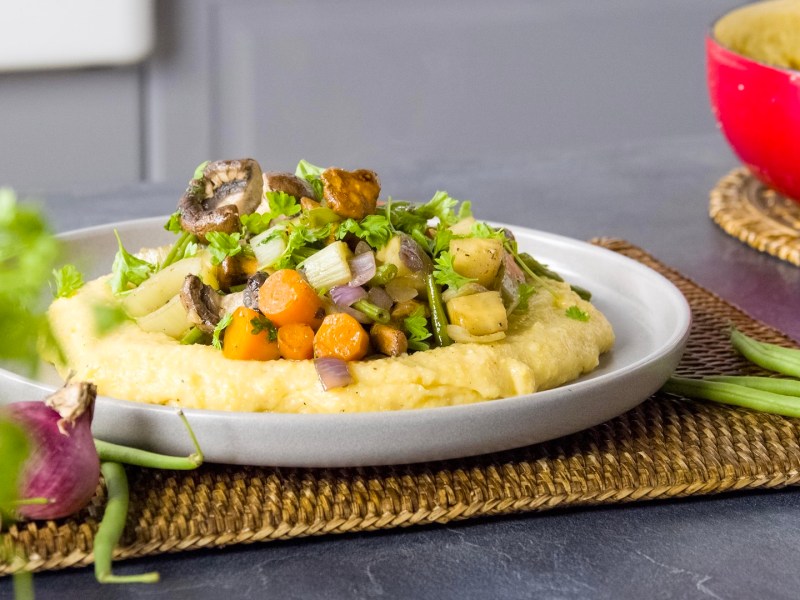 Ein Teller Gemüse-Pilzpfanne mit Polenta.
