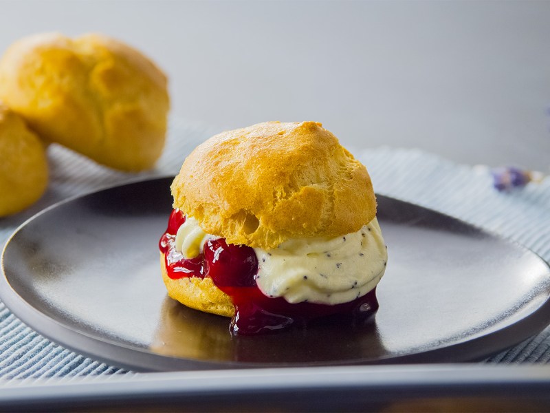 Ein glutenfreier Windbeutel auf einem dunklen Teller.