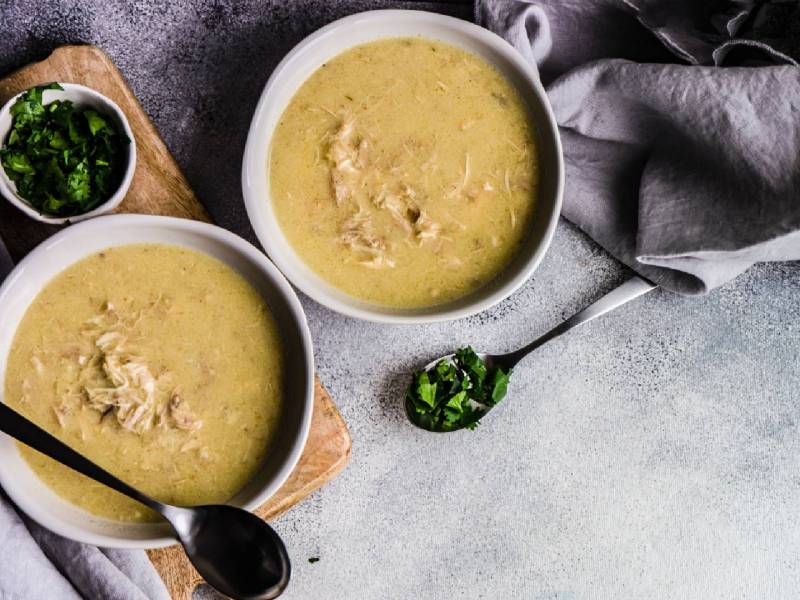 Zwei Schalen mit Chikhirtma, der georgischen Hühnersuppe auf einem Tisch, gehackter Koriander daneben