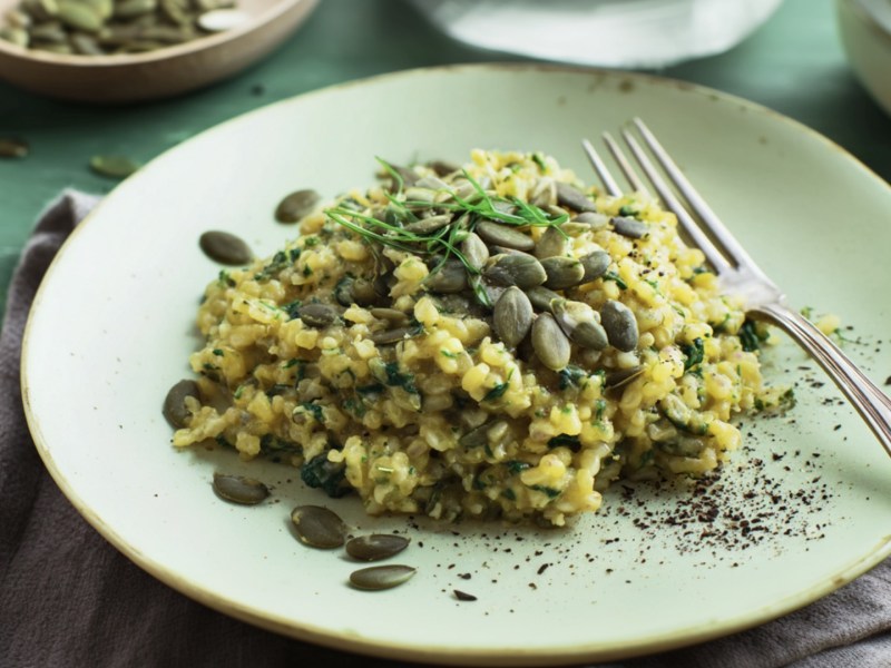 Ein Teller Hirsotto mit Kürbiskernen. Eine Gabel liegt mit auf dem Teller.