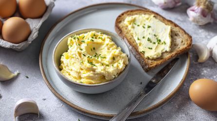 EIne Schale Knoblauch-Ei-Aufstrich, daneben ein Brot, das mit diesem bestrichen wurde.