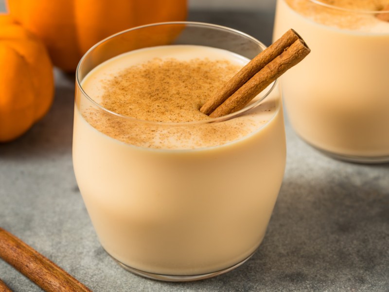 Zwei Gläser Kürbis-Eierlikör mit Zimtstange.