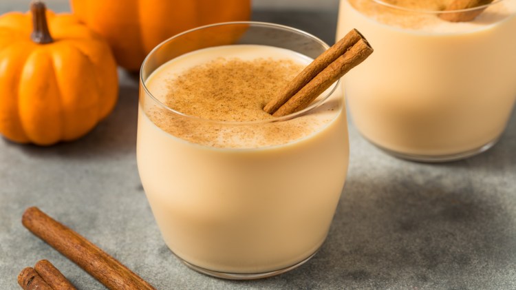 Zwei Gläser Kürbis-Eierlikör mit Zimtstange.