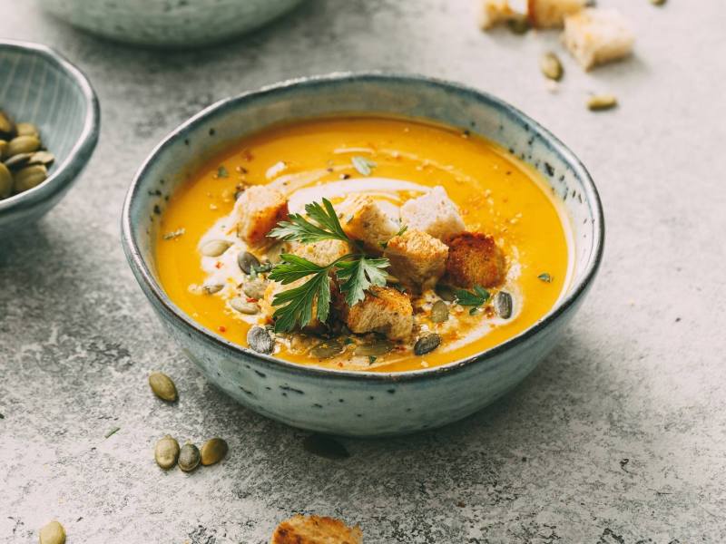 Eine Schüssel Kürbis-Petersilienwurzel-Suppe, garniert mit Croûtons.