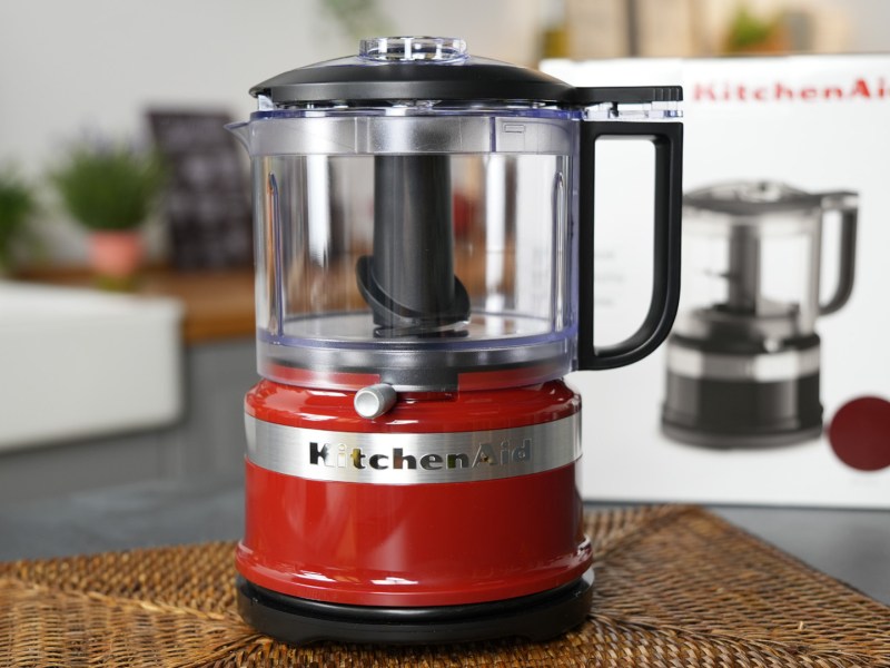 Ein Mini-Foodprocessor von KitchenAid, der auf einer Arbeitsfläche in einer Küche steht. Im Hintergrund kann man den Verpackungskarton erkennen.