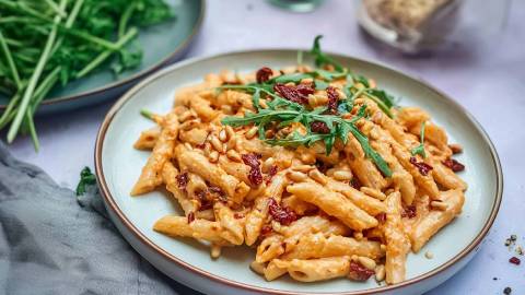 Teller mit Nudeln mit Ziegenkäsesoße, Pinienkerne und Rucola