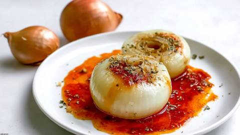 Teller mit Onion Boil, zwei ungeschälte Zwiebeln im Hintergrund