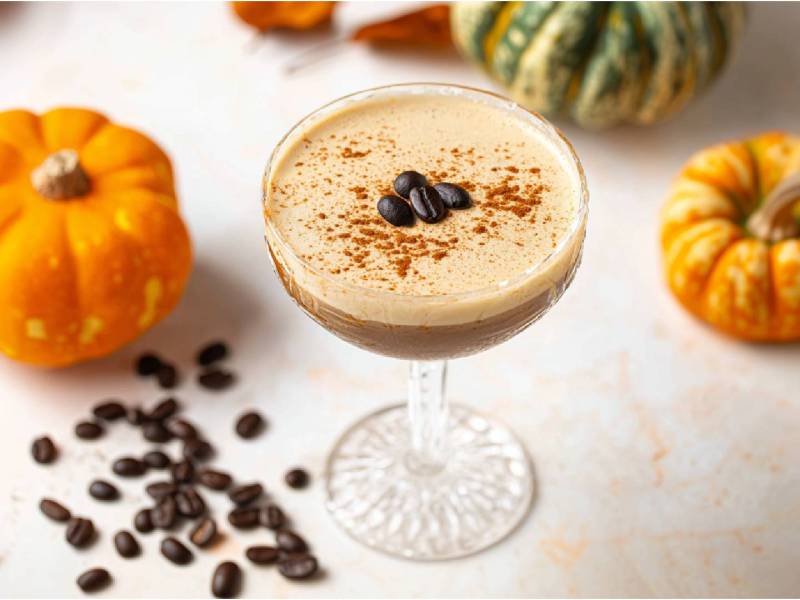 Glas mit Pumpkin Spice Espresso Martini, Zierkürbisse daneben