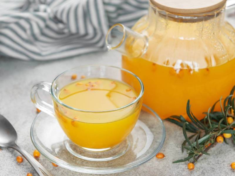 Kanne und Tasse mit Sanddorn-Tee