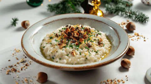 Ein Schwarzwurzel-Risotto mit karamellisierten Haselnüssen auf einem grauen Teller. Um den Teller verteilt liegen einige Haselnüsse.