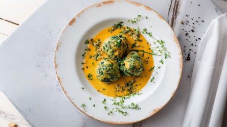 Ein Teller Spinat-Hüttenkäse-Knödel mit Kürbis-Anchovi-Sahnesoße.