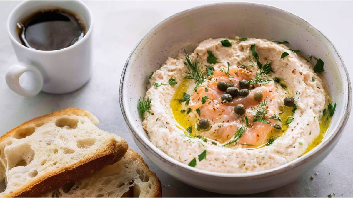 Schale mit Räucherlachs-Creme, zwei Scheiben Brot daneben, Tasse Kaffee im Hintergrund